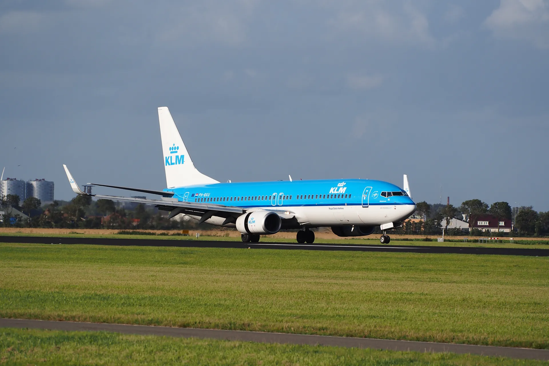 Blue and white Boeing 737-800 rolling out on a runway after landing, with a stormy sky behind it